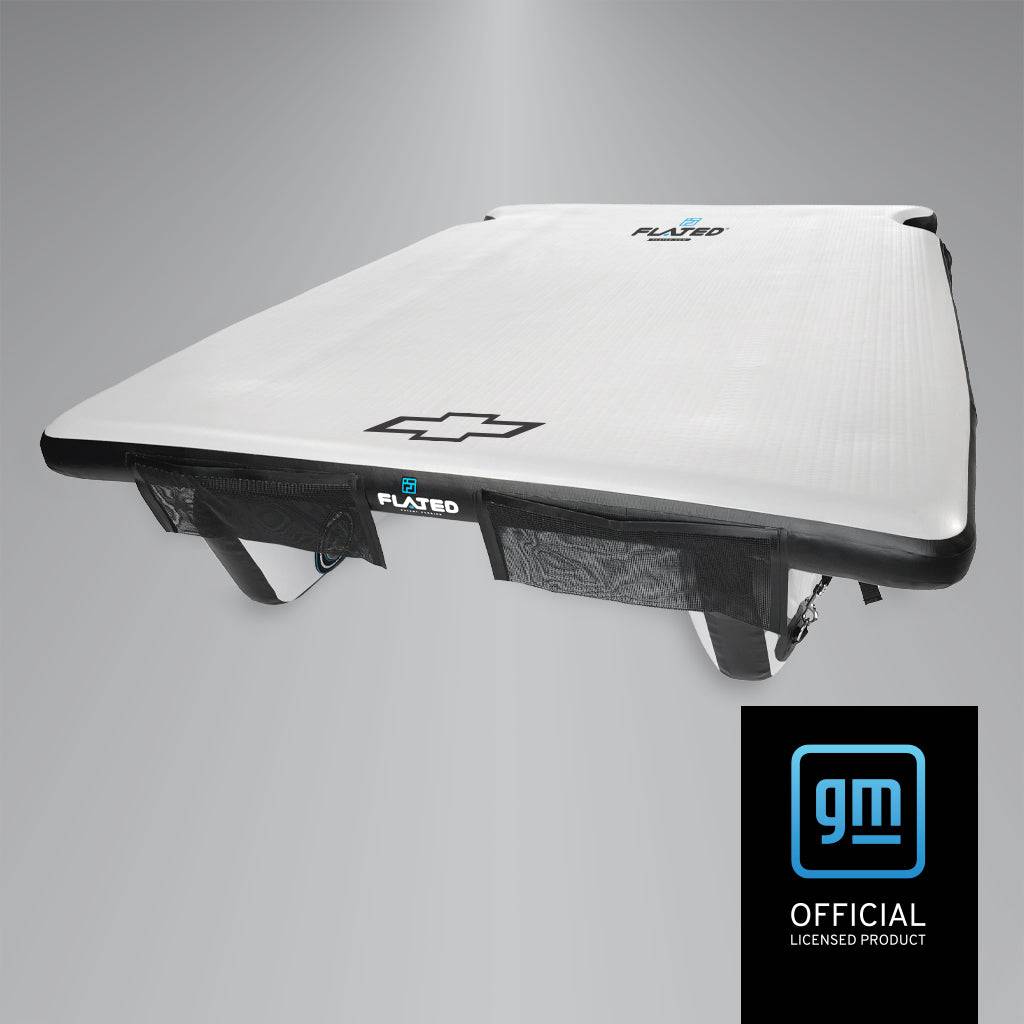 A white FLATED FULL-STANDARD DECK66 SILVERADO inflatable floating pad with black edges and a Chevrolet bowtie logo, shown at an angle. Below is a blue and black GM officially licensed product badge.