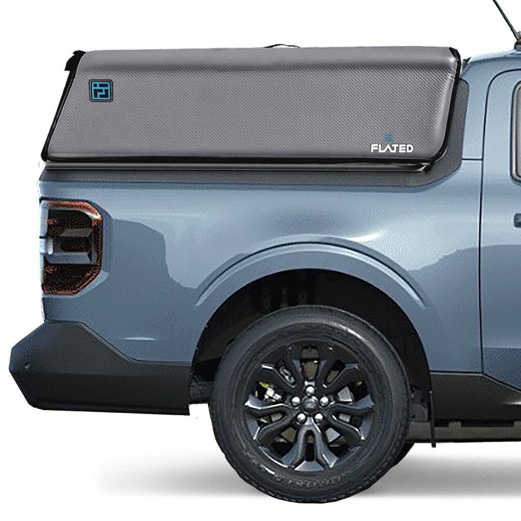 A gray pickup with a black FLATED COMPACT-MAVERICK CAP46 inflatable truck topper, partially covering the bed. The topper displays the FLATED brand name and a small blue logo on the side.
