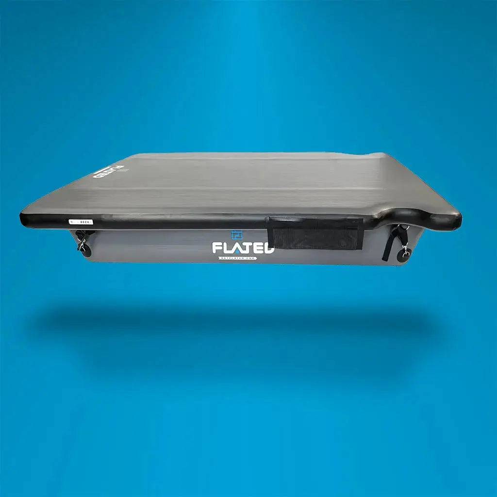 A black and gray MID-SHORT DECK50 (OPEN BOX) inflatable platform by FLATED, shown on a solid blue background. Perfect for mobile adventure rigs, this deck appears to float and casts a faint shadow below.