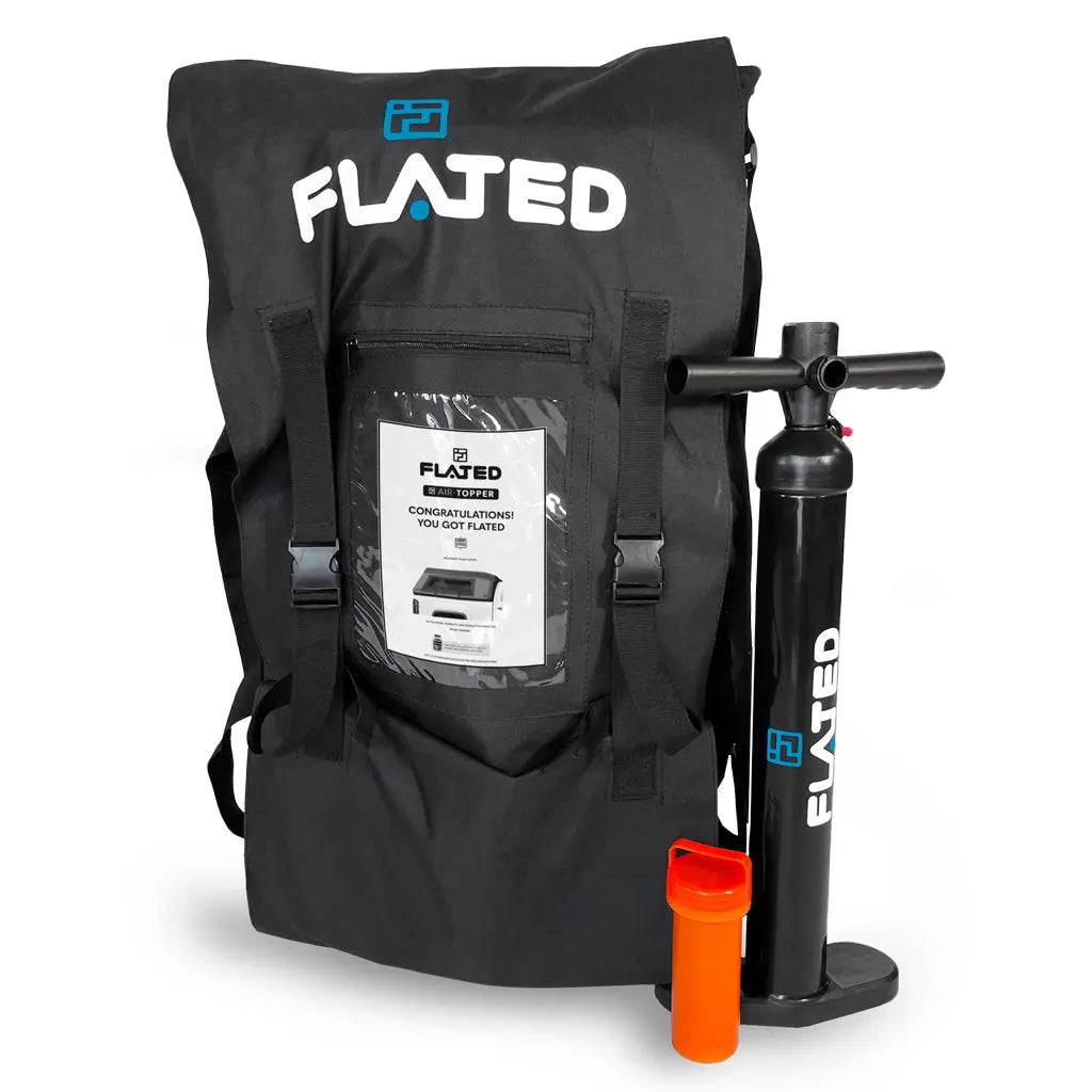 A black FLATED bag with a clear pocket for instructions sits beside a black FLATED hand pump and orange container—ideal for setting up your MID-SHORT DECK50 (OPEN BOX) or outfitting your mobile adventure rig.