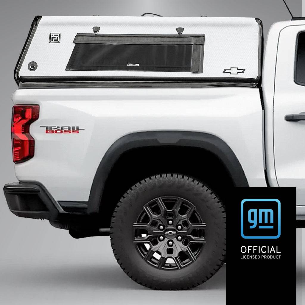 A white Chevrolet Colorado pickup with the FLATED MID-SHORT CAP50 truck cap is shown from the side. The GM Official Licensed Product logo appears in the lower right corner.