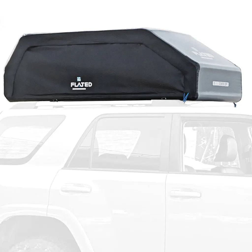 A FLATED LARGE CARRIER23 (OPEN BOX) in black and gray is mounted on top of a white SUV, shown from the side against a plain white background, making it the ideal rooftop cargo carrier for travel and gear storage.