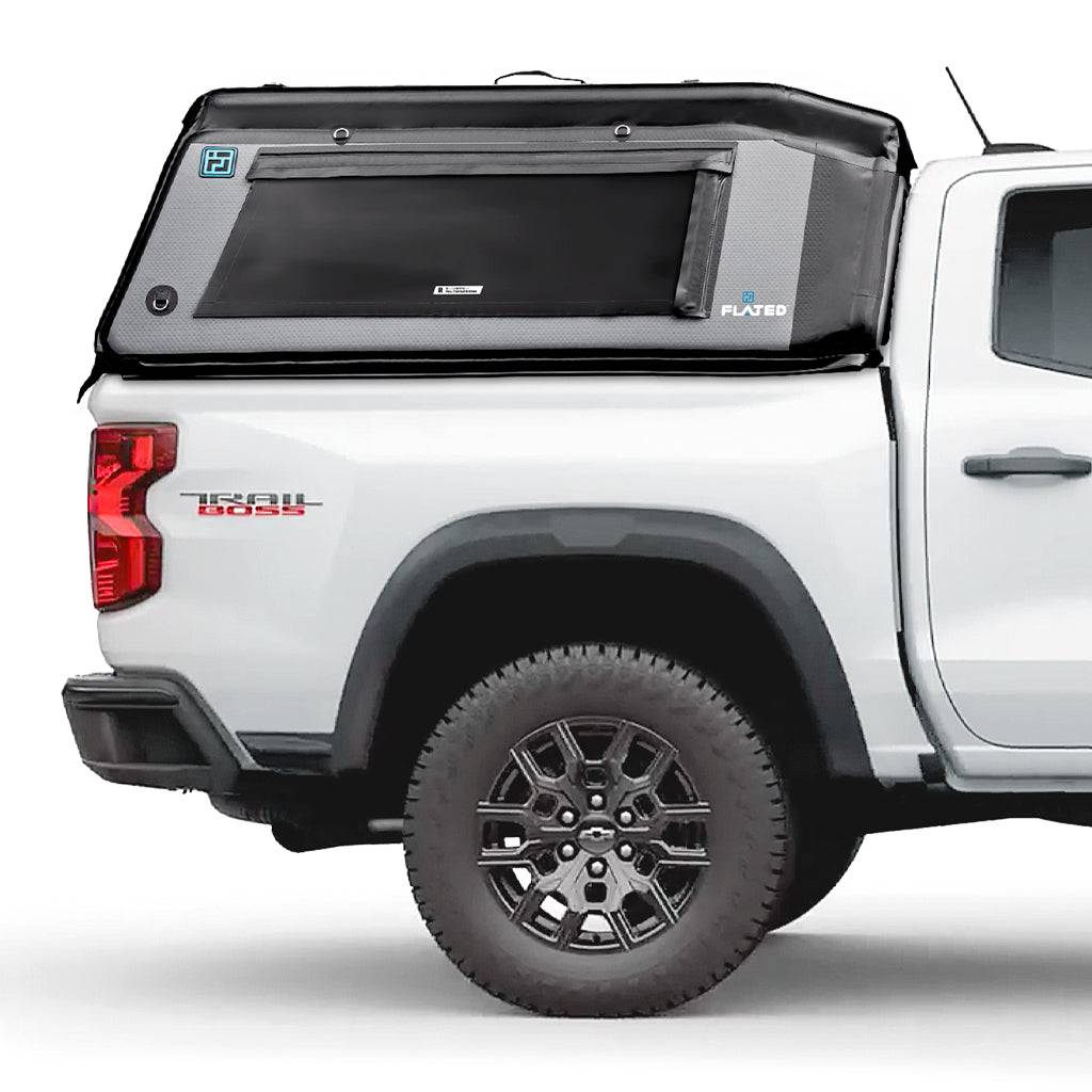 A white pickup truck in profile on a white background with a FLATED MID-SHORT MR50 gray and black Tacoma bed topper, featuring a large side window and FLATED branding on the side.