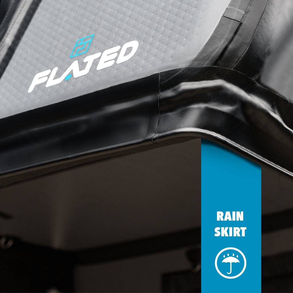 Close-up of the FLATED FULL-STANDARD DT CAP64 in grey and black, featuring the FLATED logo. A blue vertical bar labeled RAIN SKIRT with a rain icon highlights the rain skirt feature for your full-size truck bed.