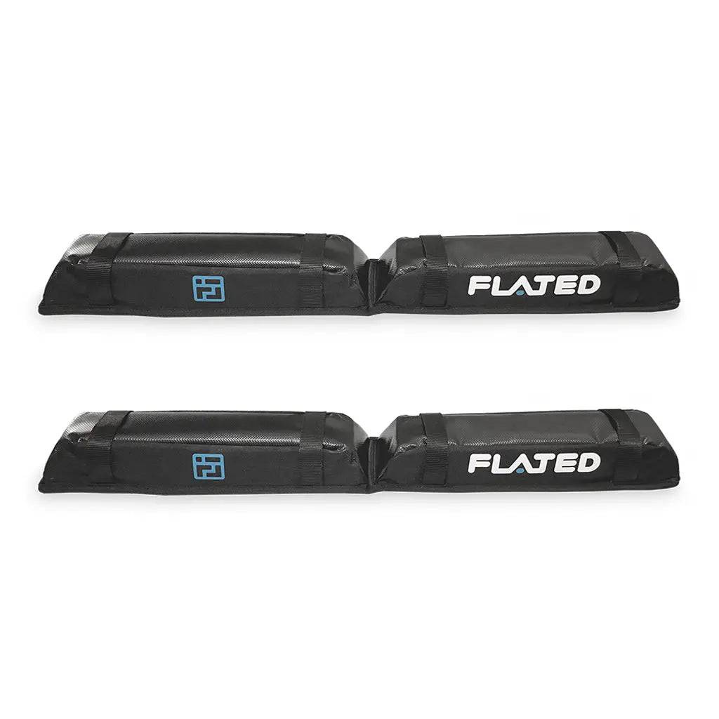 Two black FLATED SOFT RACK SET2 (OPEN BOX) pads, each with the FLATED logo and a blue geometric icon, are displayed on a white background. They fit cross bars and protect your rooftop gear.