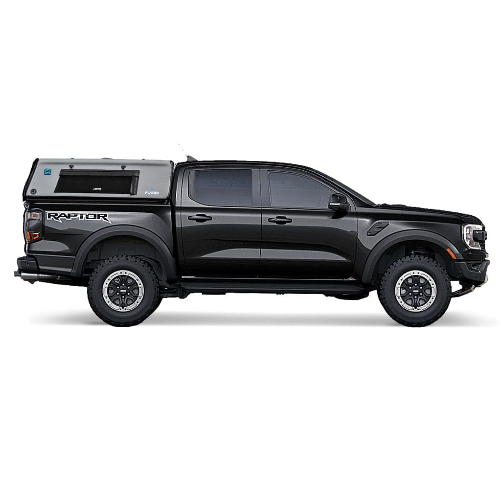 A silver pickup with a black and gray FLATED MID-SHORT CAP411 truck topper on the flatbed. The word RAPTOR appears above the rear wheel, and only the rear half of the vehicle is visible.