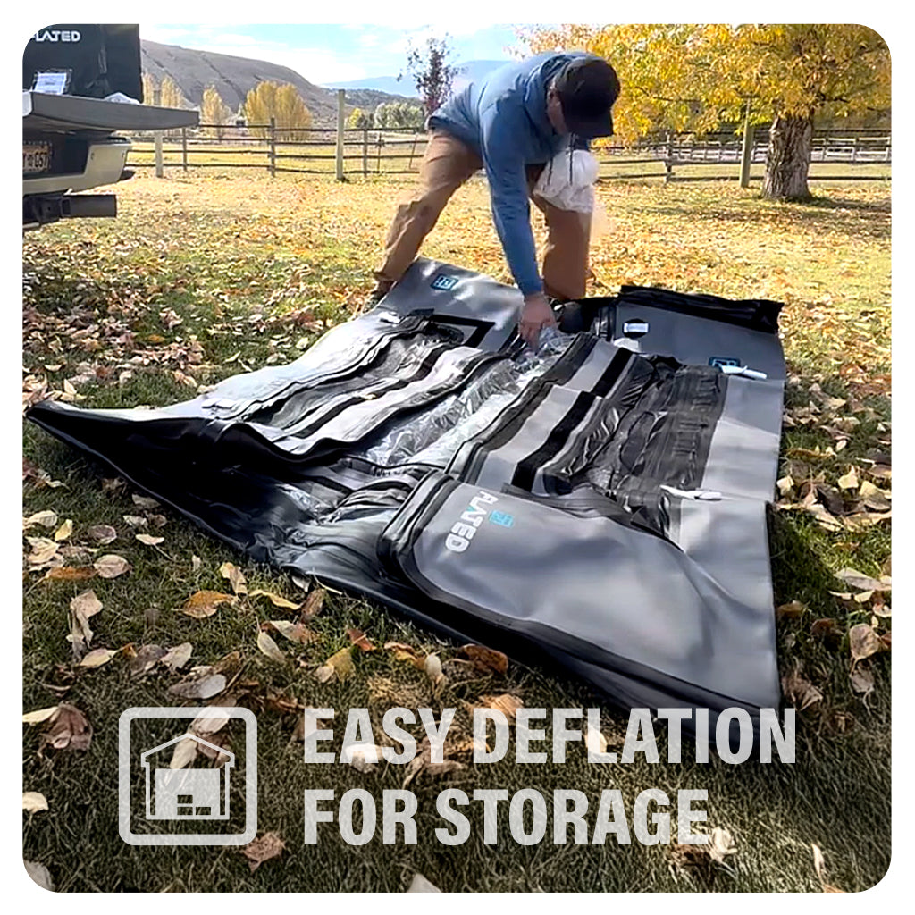 A person kneels on grass outdoors, pressing air out of a large inflatable mat to deflate it. Autumn trees are in the background. Overlay text reads, Easy Deflation for Storage with a house storage icon.