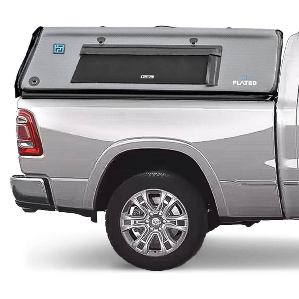 A silver pickup truck with a FLATED FULL-STANDARD DT CAP64 inflatable cap attached to the full-size bed, featuring a black side window and the FLATED logo on the gray shell.