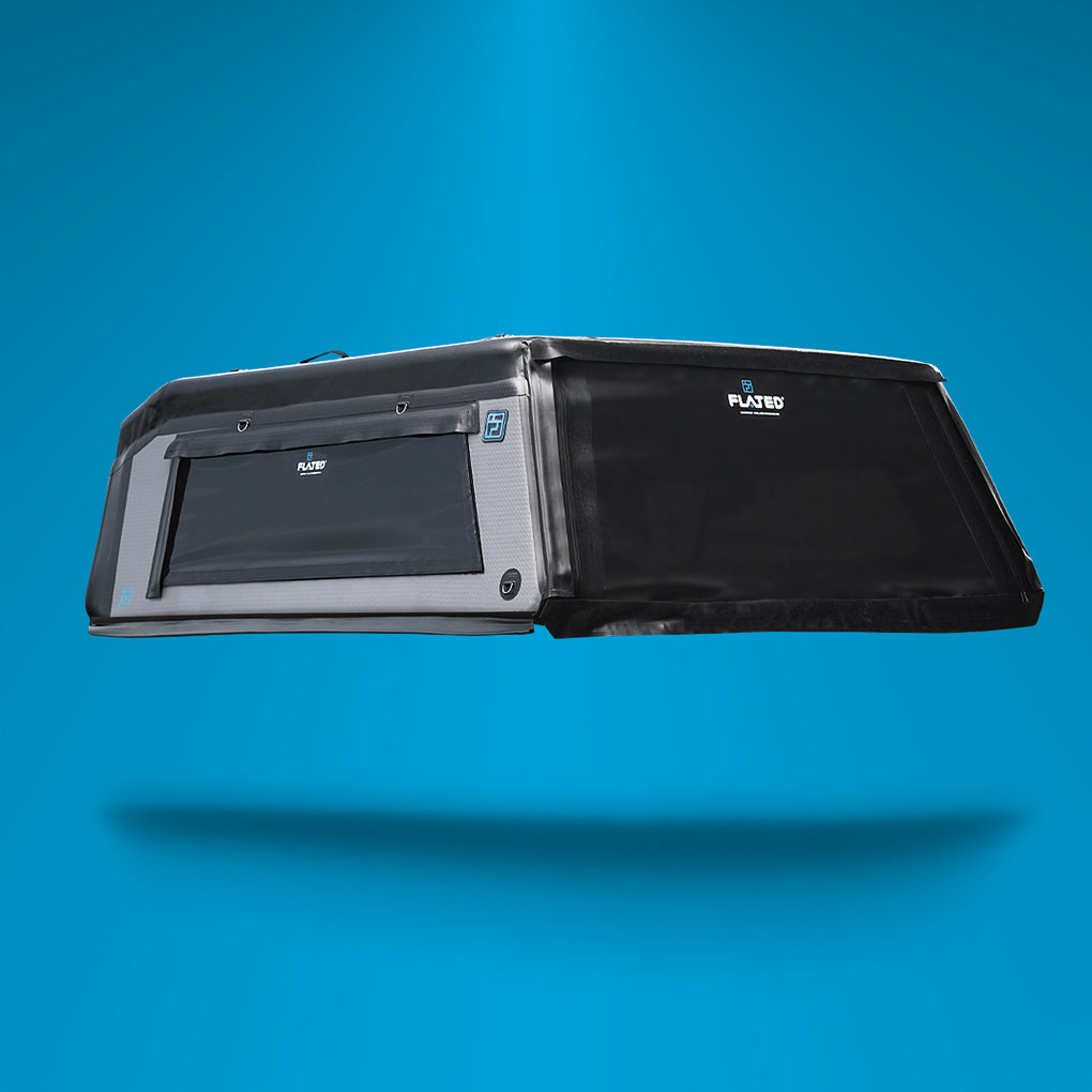 A black and gray truck bed camper shell with a side window and the Fleet logo, displayed against a solid blue background with a shadow beneath it.