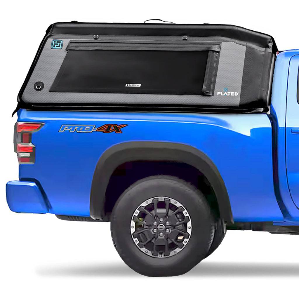 A blue pickup truck with a FLATED MID-LONG MR60 black and gray Air-Topper inflatable shell mounted over the bed. The tent is closed, highlighting a side window and branded logos on its durable fabric.