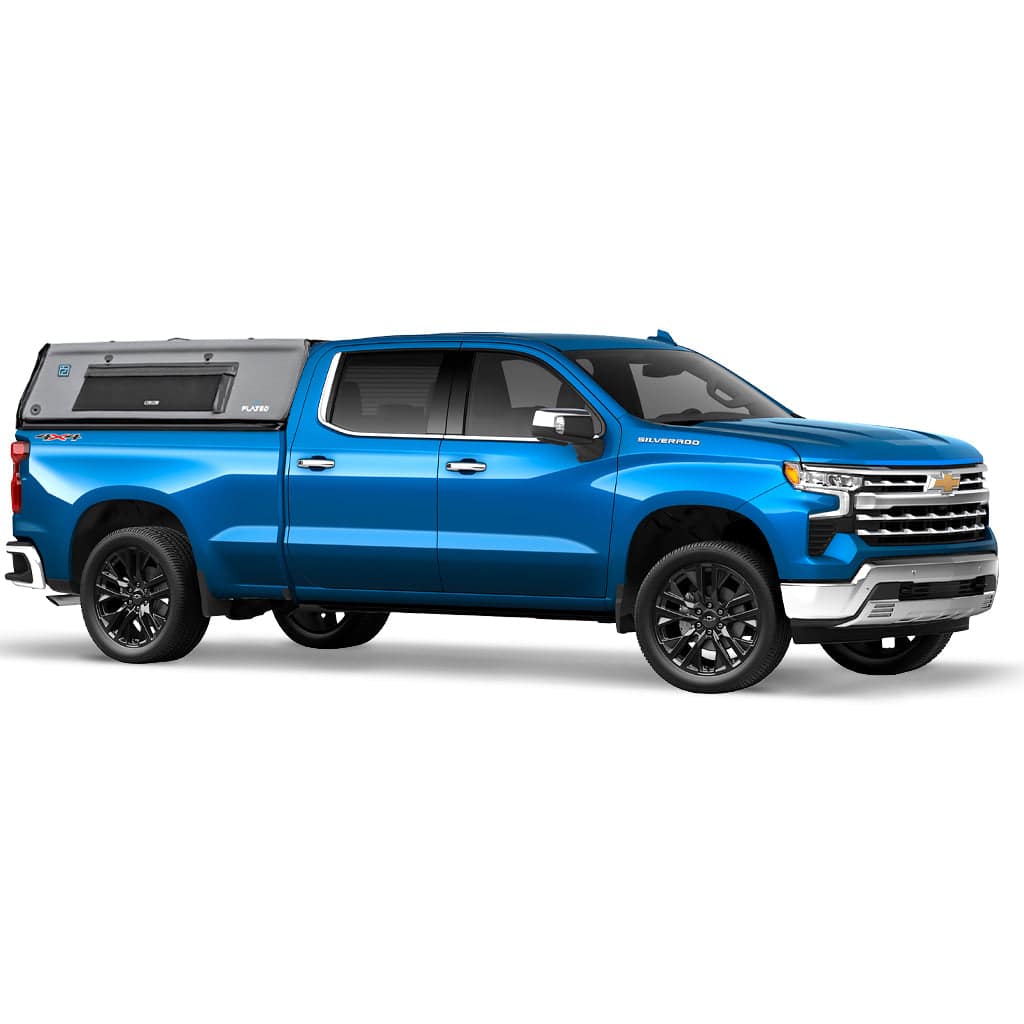 A white pickup truck with a black and gray FLATED FULL-STANDARD CAP66 inflatable truck cap is attached to its full-size bed, shown from a rear side angle. The lightweight shell features a window and prominent FLATED branding labels.