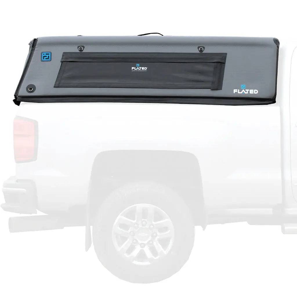 A gray FLATED FULL-STANDARD CAP66 (OPEN BOX) inflatable truck cap is installed on the bed of a white pickup, shown from the side with the full-size truck bed topper in focus and the truck partially visible.