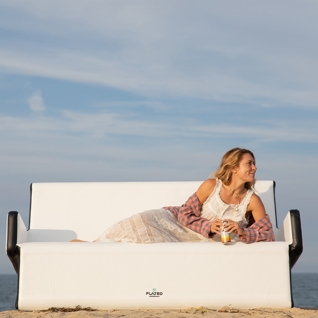 A modern white FULL-SIZE COUCH by FLATED with black armrests and edges, minimalistic design, and subtle textured pattern—ideal as portable outdoor furniture.