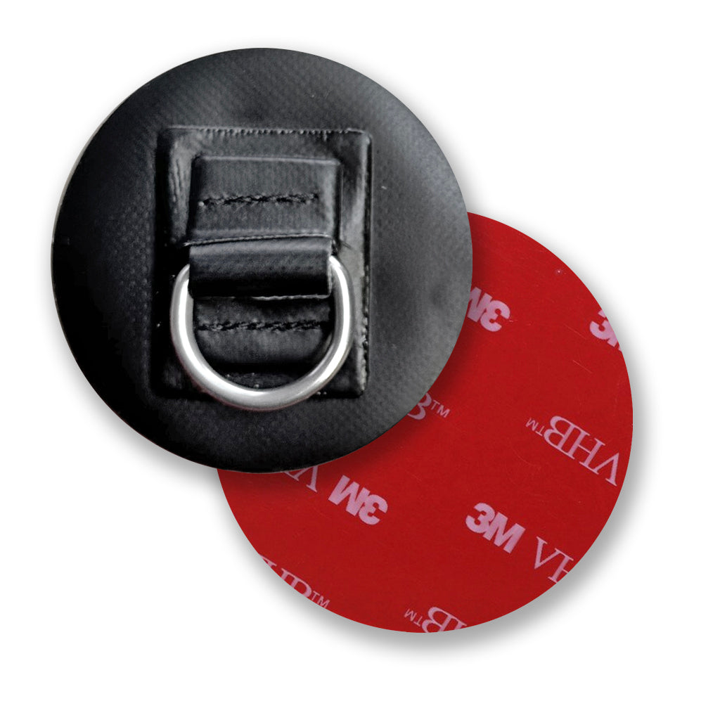 The FLATED D-RING 2PACK includes two black circular patches with stitched rectangular sections, each featuring a silver metal D-ring at the center. These textured, weather-resistant anchor points can be partially overlapped.