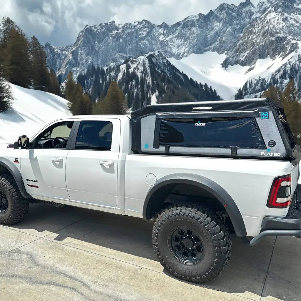 A white pickup truck features a FLATED FULL-STANDARD MR64 (OPEN BOX) inflatable truck shell in black and gray on its bed, shown in side profile against a plain white background.