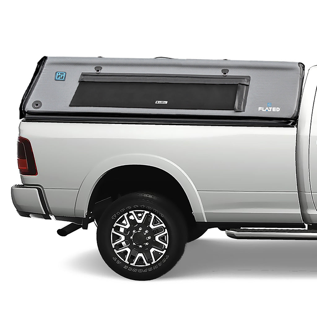 A white pickup truck with a FLATED FULL-LONG CAP80 black and gray topper attached to the full-size bed, featuring a side window and a 4x4 logo on the rear side. (Mopar Affiliate)