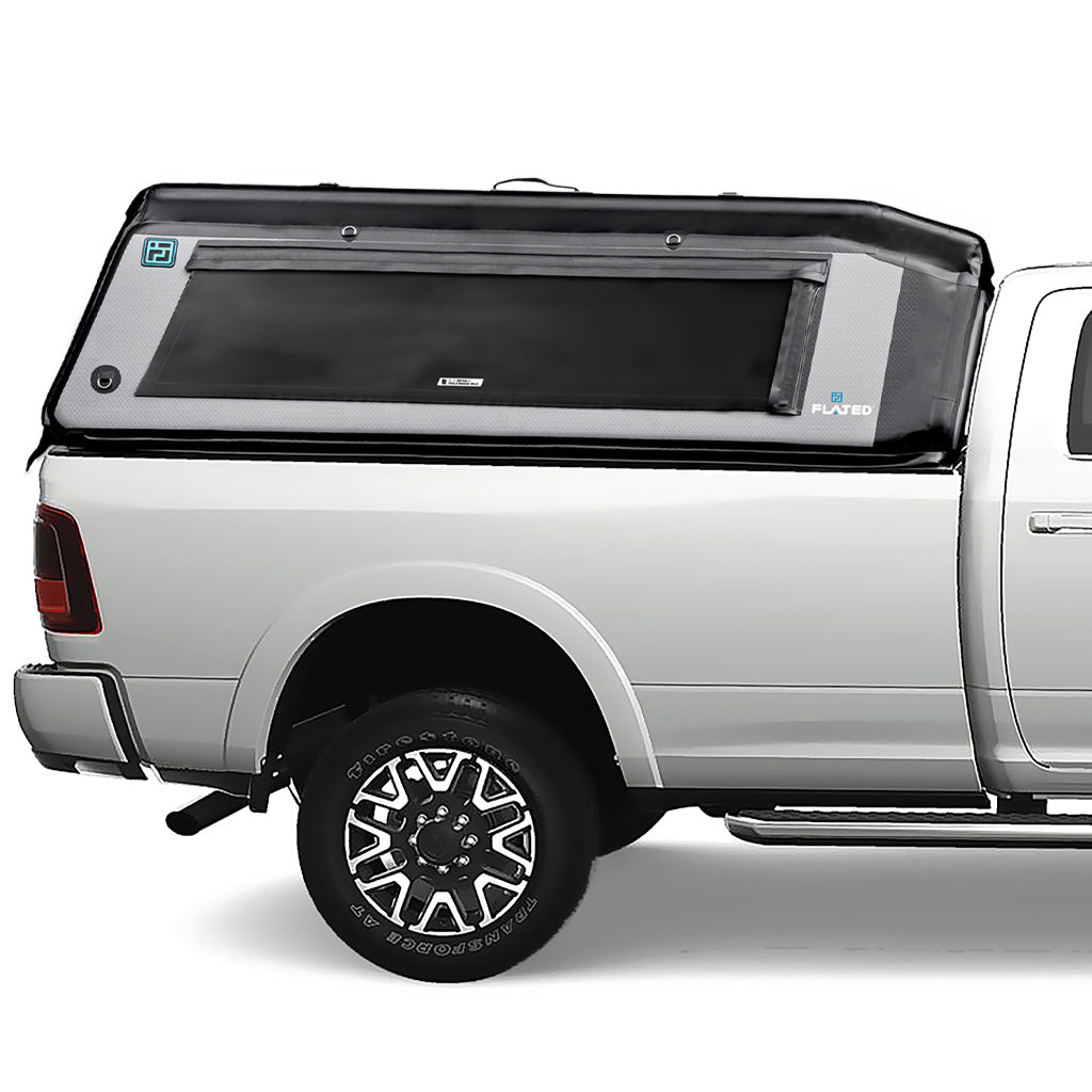 A silver pickup truck with a FLATED FULL-LONG MR80 black and gray topper attached to the full-size bed, featuring a side window and a 4x4 logo on the rear side. (Mopar Affiliate)