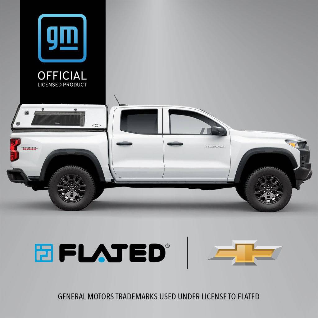 A white Chevrolet Colorado pickup with the FLATED MID-SHORT CAP50 truck cap is shown from the side. The GM Official Licensed Product logo appears in the lower right corner.