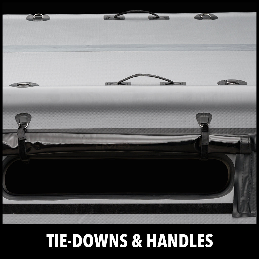 Close-up of a gray inflatable object with black tie-down straps and handles, featuring an open slot and the text TIE-DOWNS & HANDLES at the bottom.