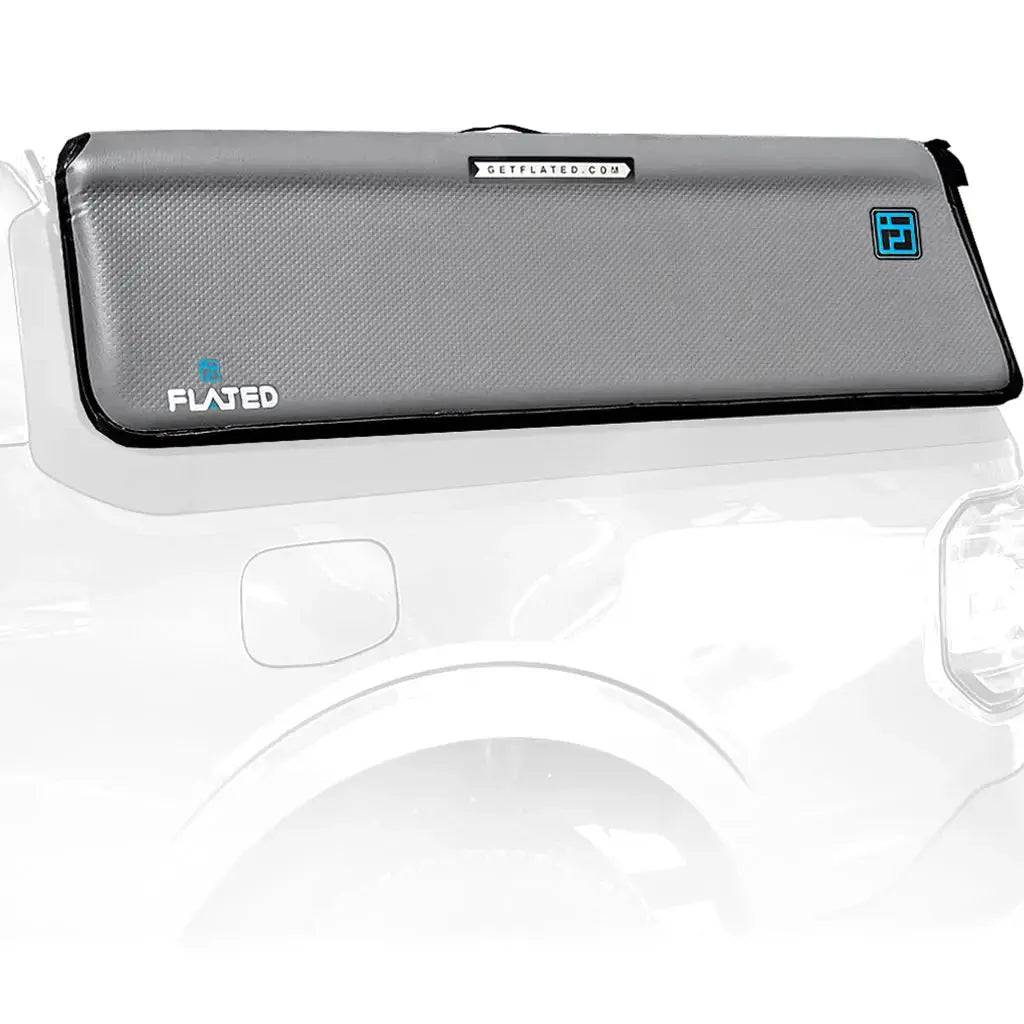 A FLATED COMPACT-MAVERICK CAP46 (OPEN BOX) inflatable truck shell, featuring durable drop-stitch technology, is shown on a white pickup. It has a gray body, black border, and blue FLATED branding for a sleek, modern appearance.