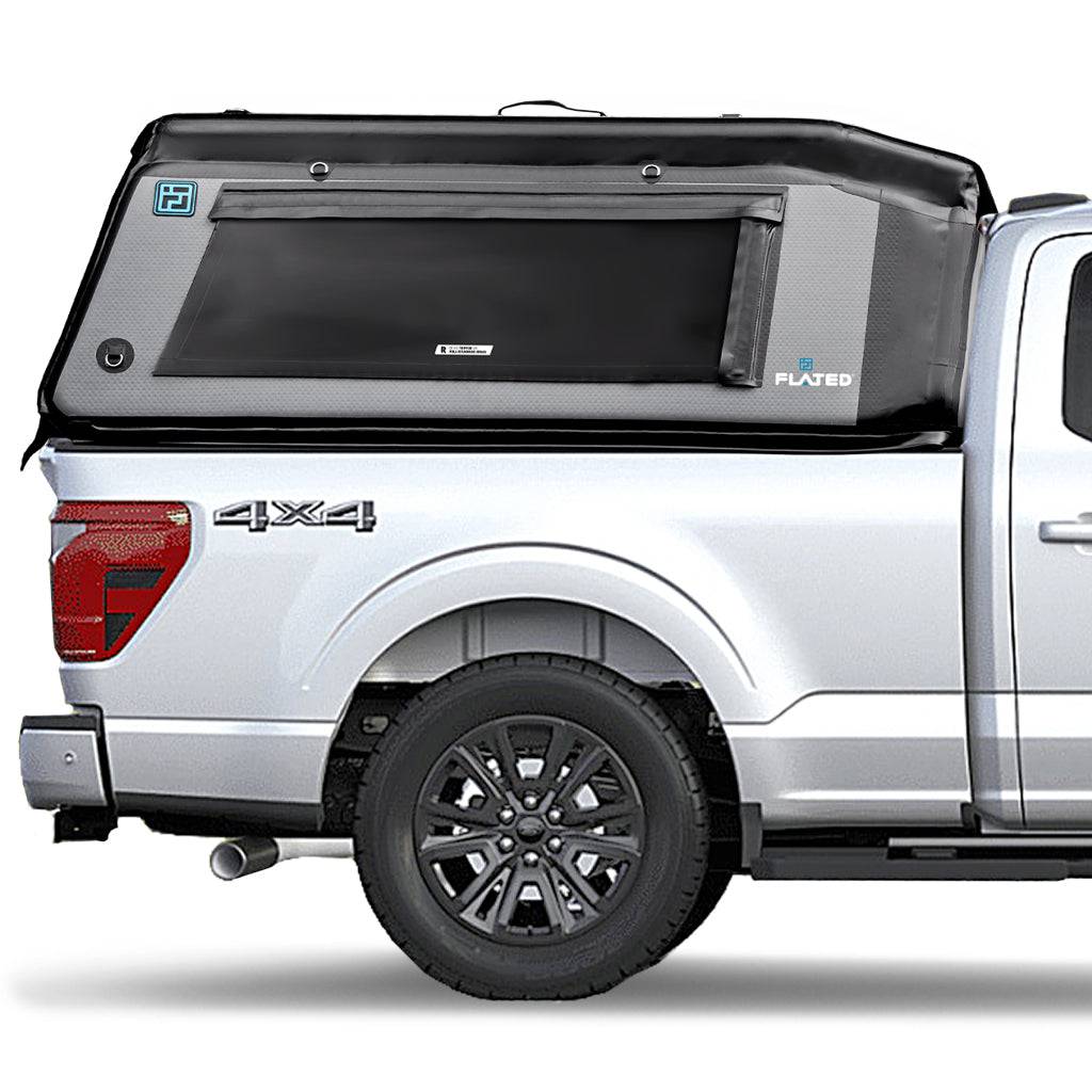 A white full-size pickup with a FLATED FULL-STANDARD MR66 black and gray truck topper, featuring a large side window, branding logos, and a 4x4 label on the side.
