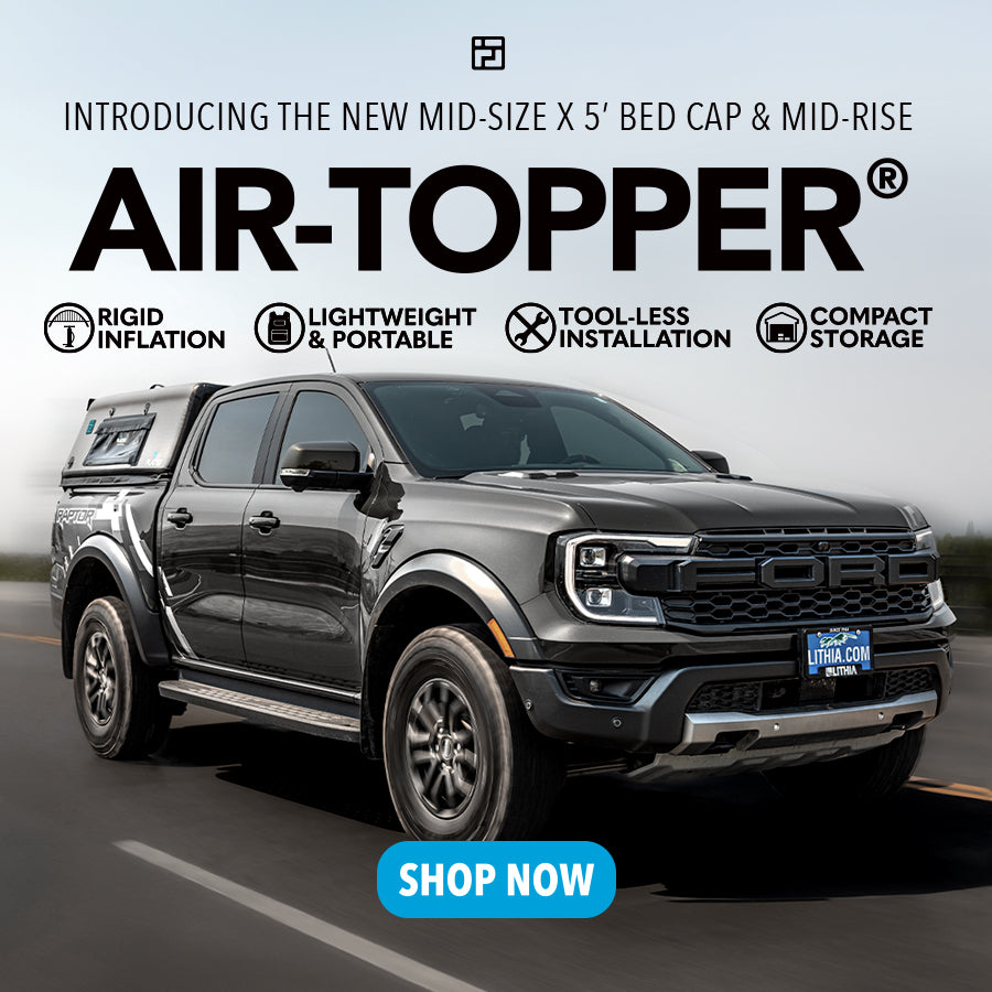 A gray pickup truck with a mid-rise 5-foot AIR-TOPPER bed cap drives on a road. Text highlights features: rigid inflation, lightweight, portable, tool-less installation, and compact storage. A Shop Now button is at the bottom.