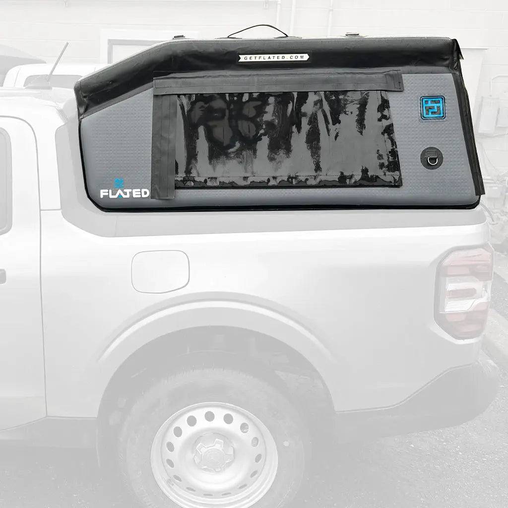 A FLATED COMPACT-MAVERICK MR46 (OPEN BOX) inflatable truck bed topper, in black and gray with a large side zippered window, is installed on the back of a white pickup truck.