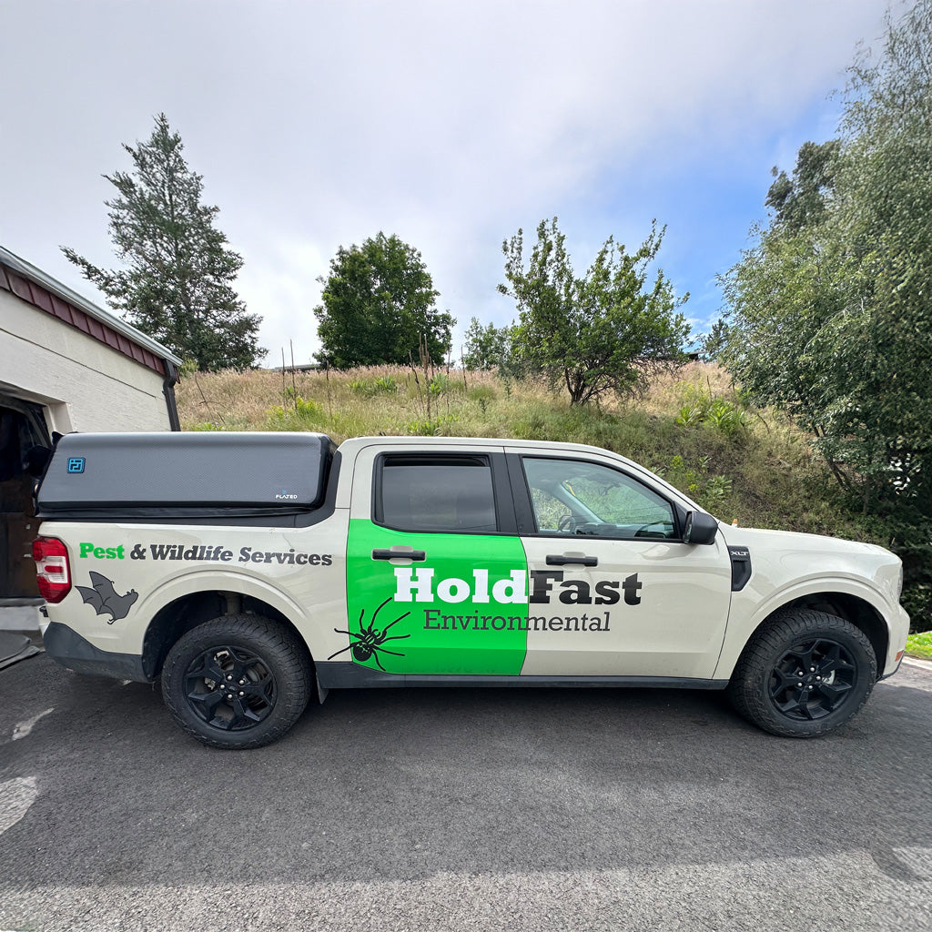 White truck with 'HoldFast Environmental' branding parked outdoors.